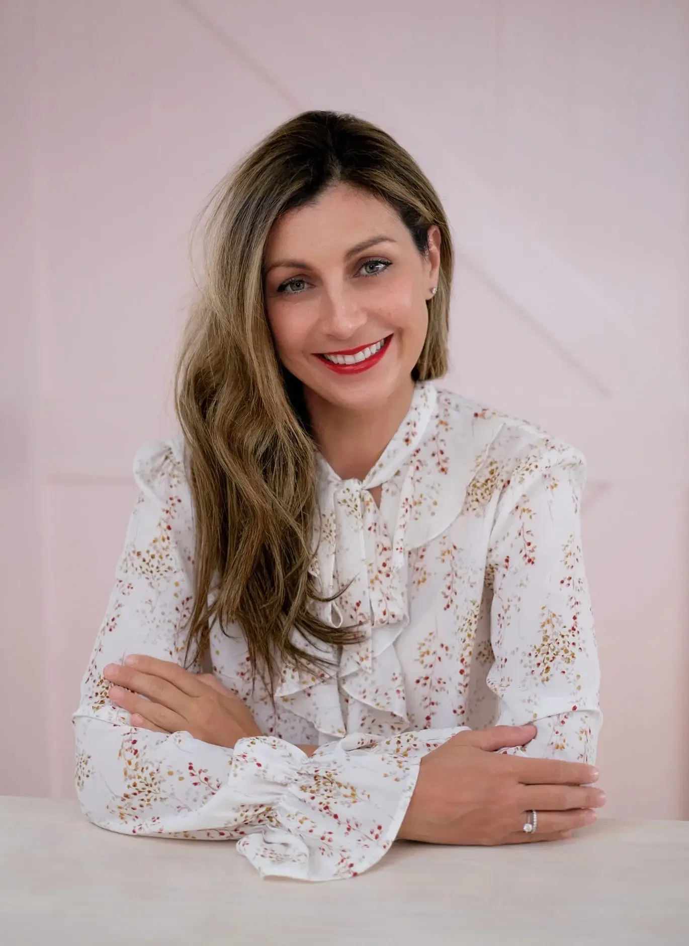 Woman in floral blouse, arms crossed.